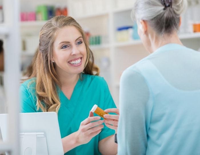 Young female pharmacy technician helping a customer