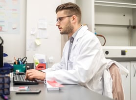 young male pharmacist working at his desk while in a hospital pharmacy